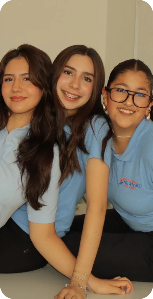 Tres alumnas de Newport High School sonriendo juntas en el salón