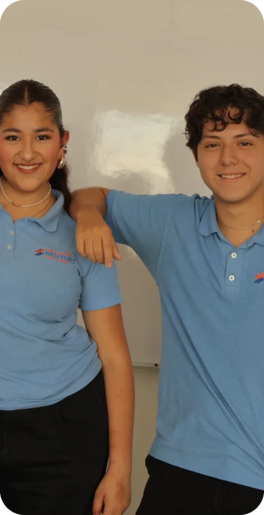 Alumna y alumno de Newport High School con polo azul sonriendo en el salón